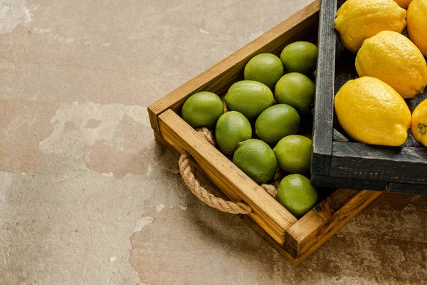 ripe lemons and limes in wooden boxes on weathered surface