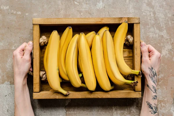 Cropped View Woman Holding Ripe Bananas Wooden Box Weathered Surface — Stock Photo, Image