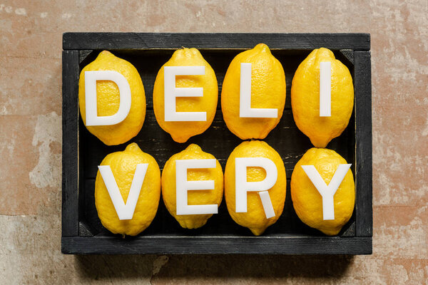 верхний вид доставки слова на лимонах в деревянном черном ящике на выветриваемой поверхности
