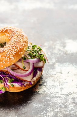 Taze lezzetli simit, et, kırmızı soğan, krem peynir ve desenli gri yüzey üzerinde lahanalar.