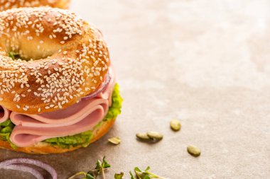 fresh delicious bagel with sausage on textured surface with pumpkin seeds clipart