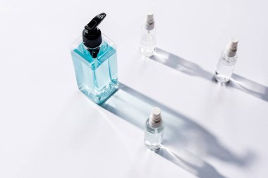 Beyaz ve gölgeli antiseptik sıvıyla şeffaf şişelerin yüksek açılı görüntüsü 