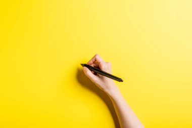 cropped view of designer holding stylus on yellow  clipart