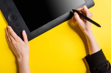 Siyah stilini sarı üzerine boş ekran çizen tabletin yanında tutan tasarımcının kırpılmış görünümü 