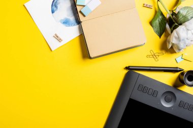 Boş ekranlı tabletin üst görünümü, klipler, stil, resim, boş not defteri ve sarı üzerine çiçek 