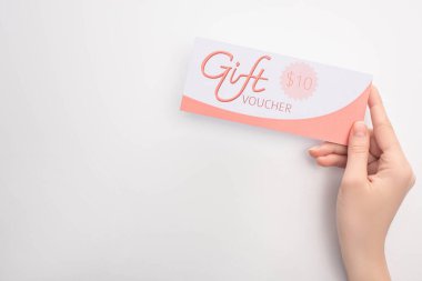 Top view of woman holding gift voucher with 10 dollars sign on white surface clipart