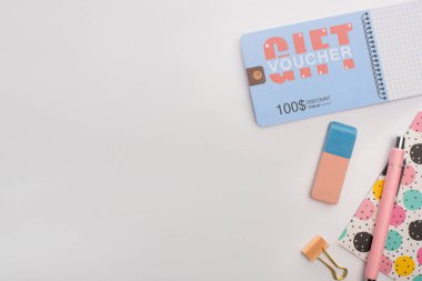 Kırtasiye malzemelerinin yanında 100 dolarlık indirim kuponu ve beyaz arka planda defter.