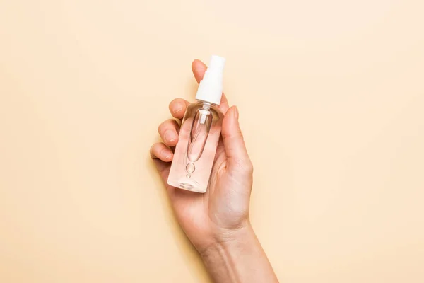 cropped view of female hand with spray bottle with sanitizer on beige