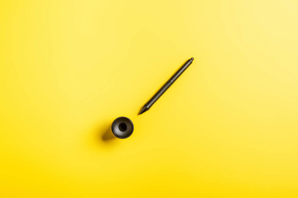 top view of black stylus near holder on yellow 