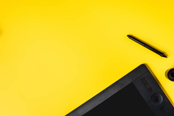 top view of drawing tablet and black stylus on yellow 