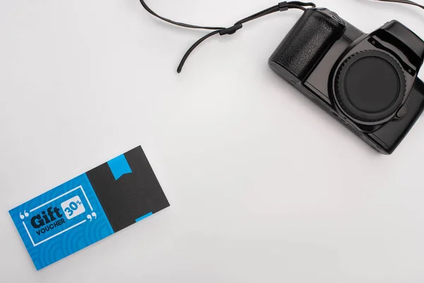 白い背景に青いギフト券とデジタルカメラのトップビュー — ストック写真
