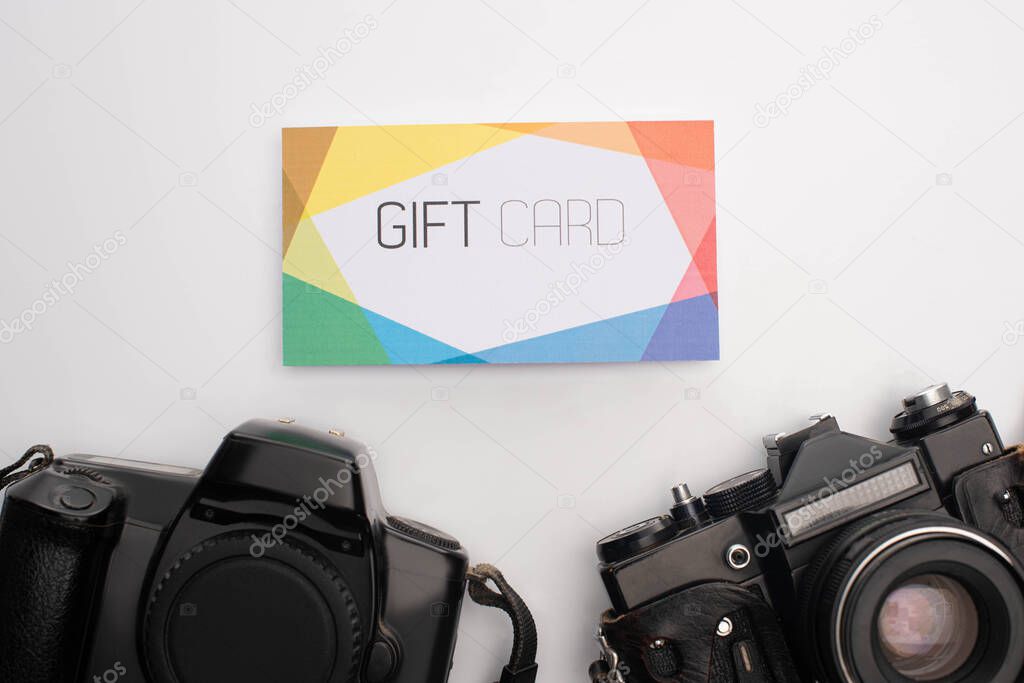 Top view of colorful gift card and digital cameras on white background