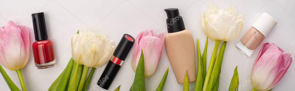 Panoramic crop of decorative cosmetics and tulips on white background