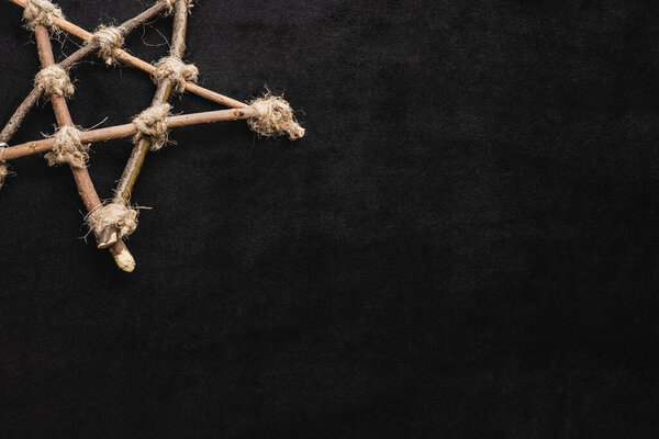top view of pentagram with wooden sticks on black