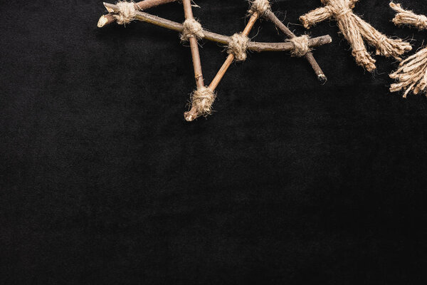 top view of voodoo doll near pentagram with wooden sticks on black