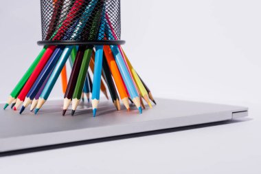 beyaz arka planda modern dizüstü bilgisayarda kalem tutacağında renkli kalemler