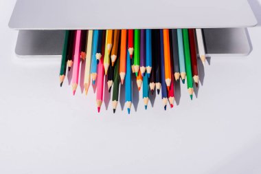 Beyaz arkaplanda modern dizüstü bilgisayarda renkli kalemler