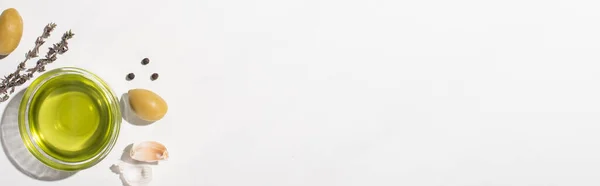 緑のオリーブ ニンニク ハーブ 黒コショウの近くのボウルのオリーブオイルの上からの眺め白い背景 パノラマの向き — ストック写真