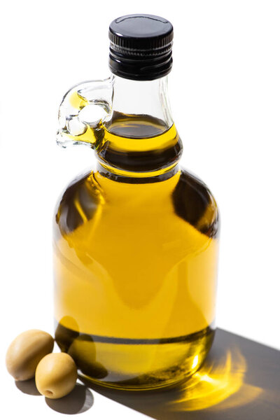 olive oil in bottle near green olives on white background