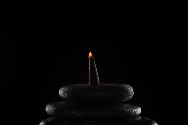 burning incense on stones isolated on black background clipart