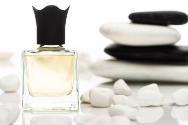 selective focus of home perfume in bottle near spa stones on white background clipart