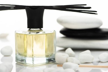 selective focus of aroma sticks and perfume near spa stones isolated on white clipart