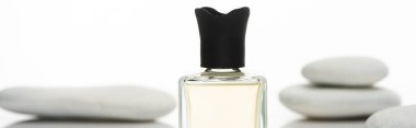 selective focus of home perfume in bottle near spa stones isolated on white background, panoramic shot clipart