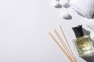 top view of aroma sticks with perfume in bottle near spa stones and towel on white background clipart