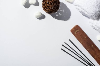 Aroma çubuklarının üst görüntüsü, ahşap tezgah, taşlar, pamuk havlular ve beyaz arka planda dekoratif top.