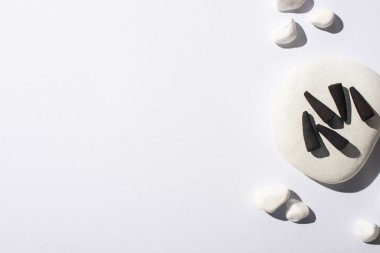 top view of black incense cones, stones on white background clipart