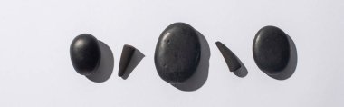 top view of black incense cones and spa stones on white background, panoramic shot clipart