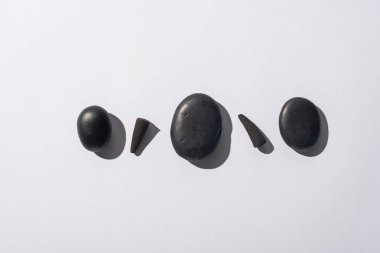 top view of black incense cones and spa stones on white background clipart