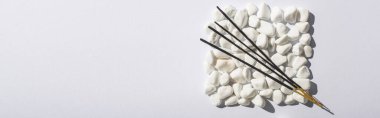 top view of aroma sticks on square made of stones on white background, panoramic shot clipart