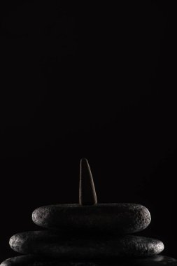 incense cone on stones isolated on black background clipart