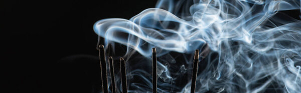 burning aroma sticks with smoke on black background, panoramic shot
