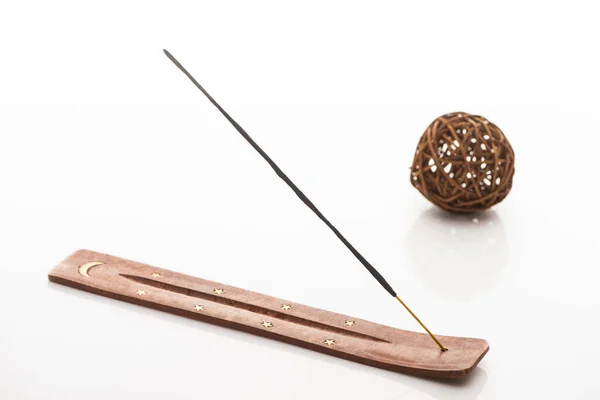 selective focus of aroma stick on wooden stand with moon and stars near decorative ball on white background