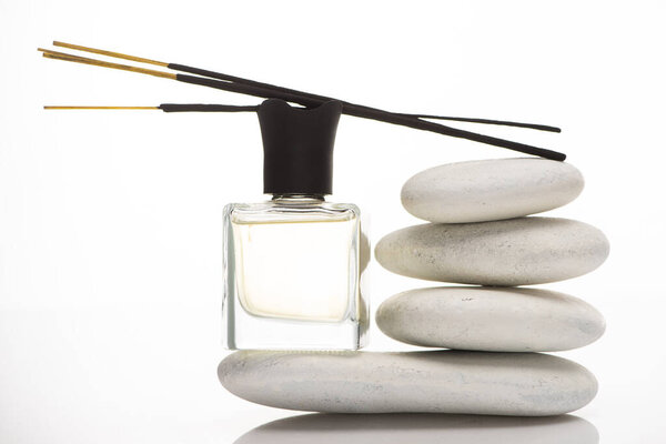 aroma sticks on perfume in bottle near spa stones on white background