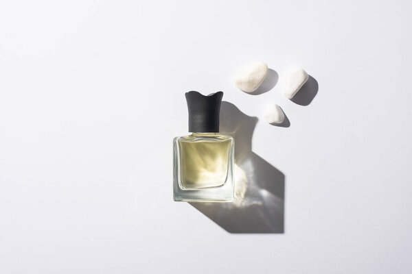 top view of home perfume in bottle near stones on white background