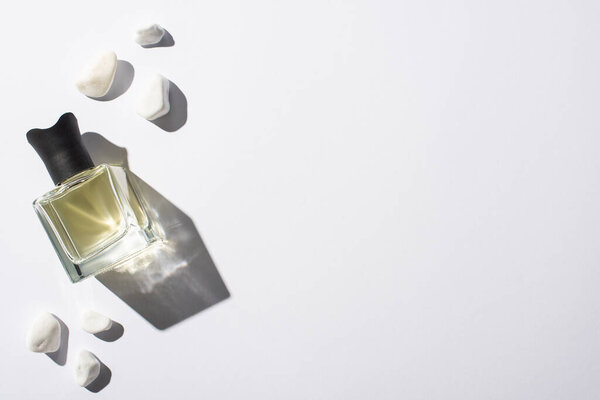top view of home perfume in bottle near stones on white background
