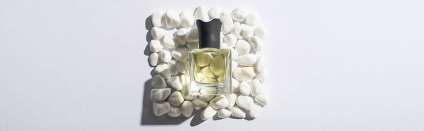 top view of home perfume in bottle on square made of stones on white background, panoramic shot