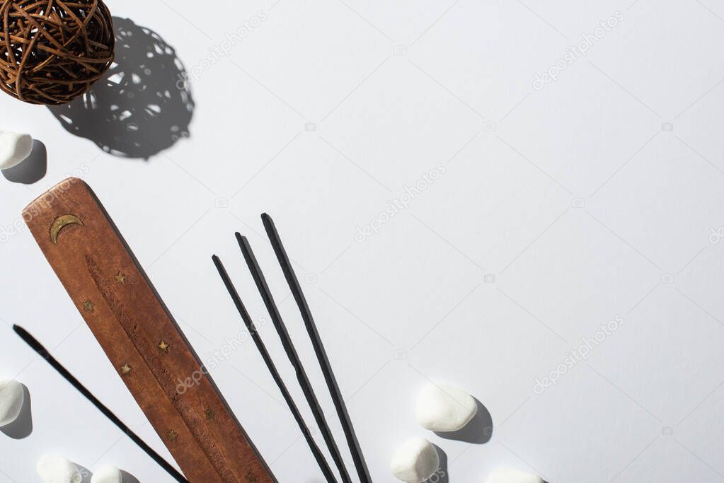 top view of aroma sticks, stones, wooden stand and decorative ball on white background
