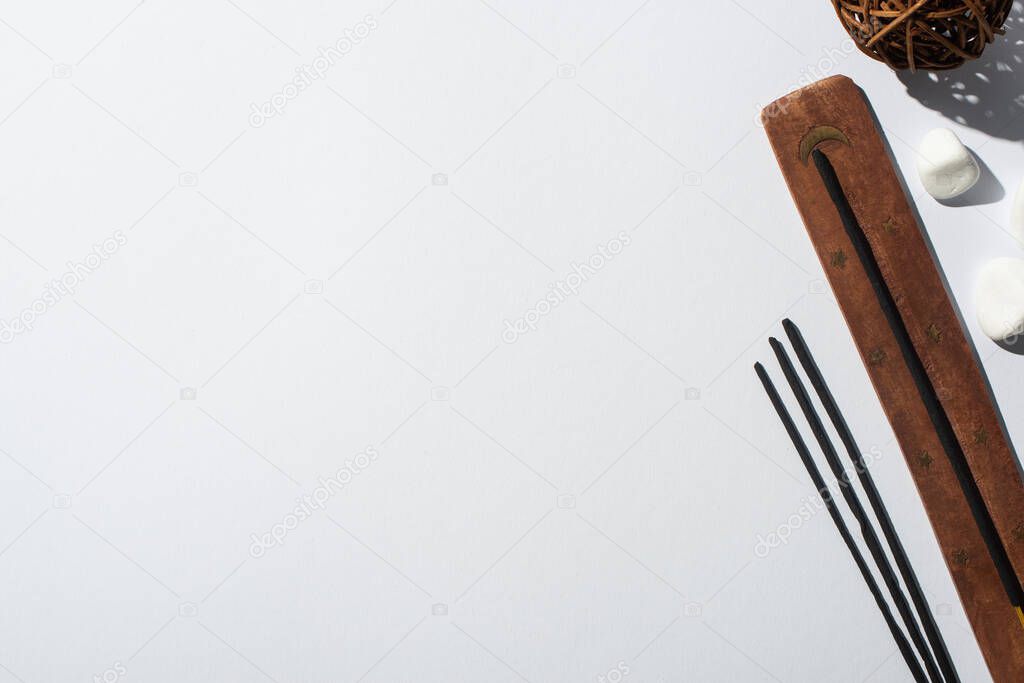 top view of aroma sticks, stones, wooden stand and decorative ball on white background