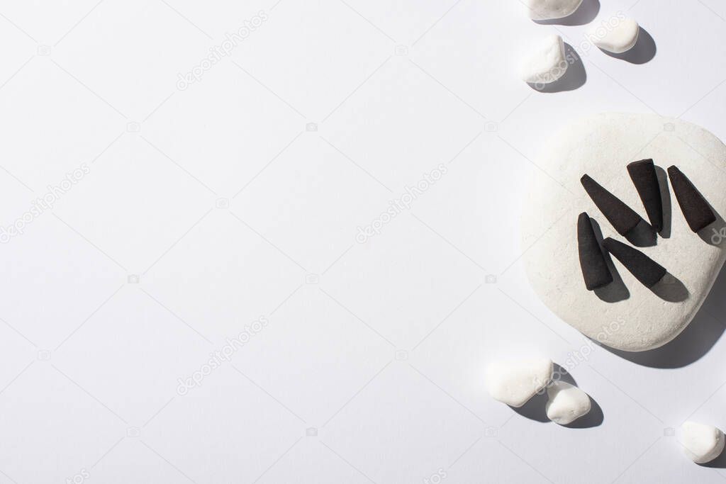 top view of black incense cones, stones on white background