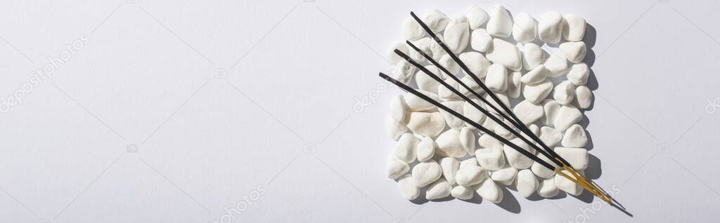 top view of aroma sticks on square made of stones on white background, panoramic shot
