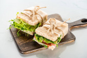 friss zöld szendvicsek avokádóval és hús fa vágódeszkán fehér felületen
