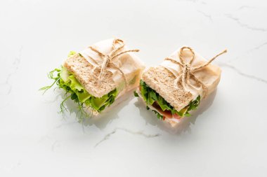 Taze yeşil sandviçler, beyaz mermer yüzeyde avokado ve jamon.
