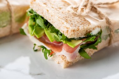 Taze yeşil sandviçin beyaz mermer yüzeyinde jamon olan görüntüsünü kapat.