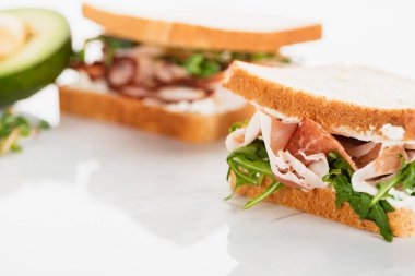 Beyaz yüzeyde roka ve prosciutto ile taze sandviçin seçici odak noktası