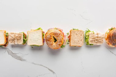 Taze sandviçler ve mermer beyaz yüzey üzerinde simit ile düz yatıyordu.
