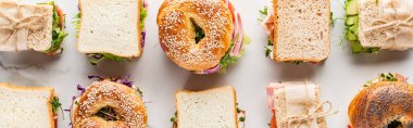 flat lay with fresh sandwiches and bagels on marble white surface, panoramic shot clipart